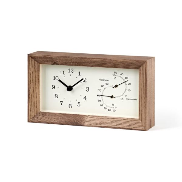 brown frame surrounds an off white face, which displays a thermometer and a hygrometer as well as clock face