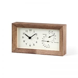 brown frame surrounds an off white face, which displays a thermometer and a hygrometer as well as clock face