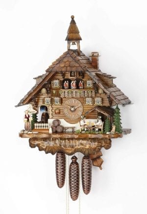 Beer drinkers sit in front of the chalet, which is ornate and has a bell tower to the top