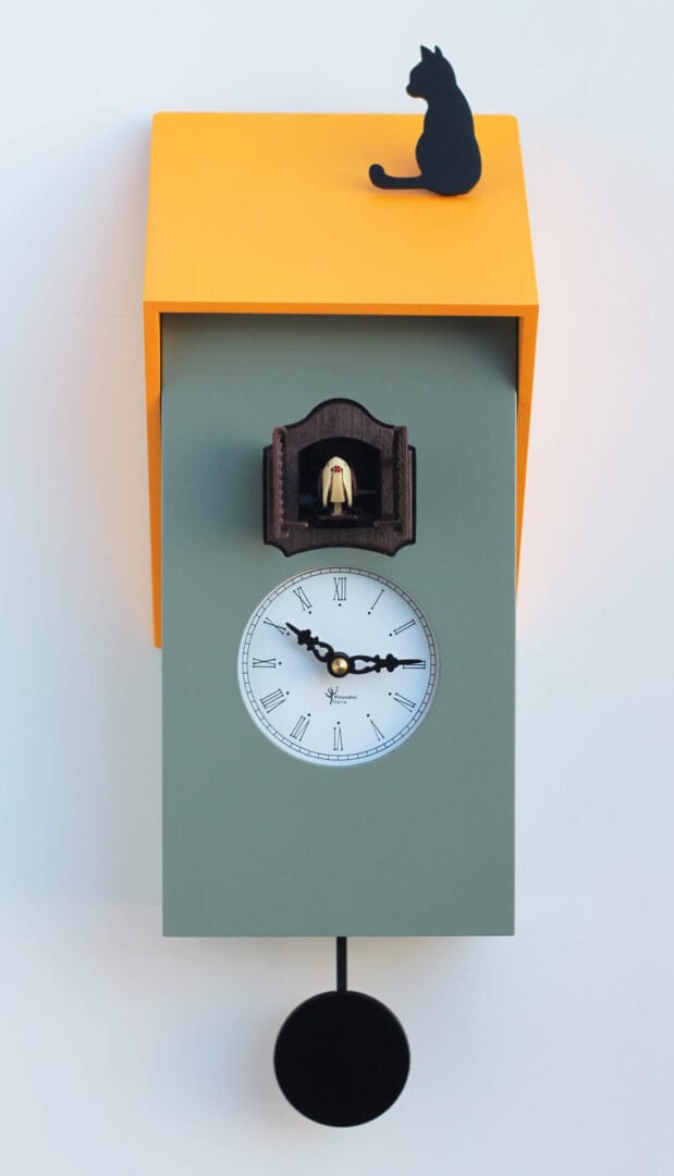 Cucu Vicenza clock in grey and yellow. The mdf clock has a grey body with yellow roof on which sits as black cat. The clock face is white with black numbers and hands and the cuckoo appears above the clock face