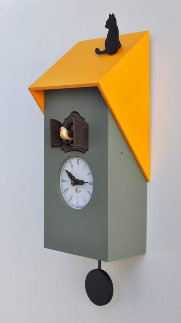 Side view of a grey clock with a yellow roof on which sits a black cat. The clock face is in white and the cuckoo appears from its house just above the face