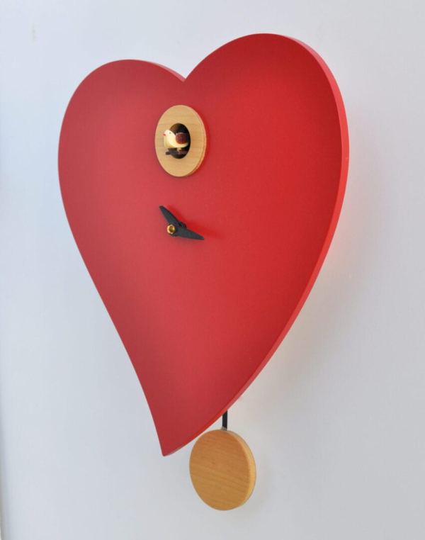 Side view of a red heart shaped clock with natural wood and black trim, the clock face has no numbers and black hands