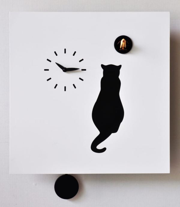 a black cat sits in wait for the cuckoo, an unusual clock with a white background