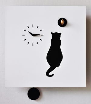 a black cat sits in wait for the cuckoo, an unusual clock with a white background