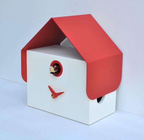Side view of the Dotto cuckoo clock, which is made of white MDF with a thin metal pitched roof in red, and also has red hands. The cuckoo appears from a small hole above the hands
