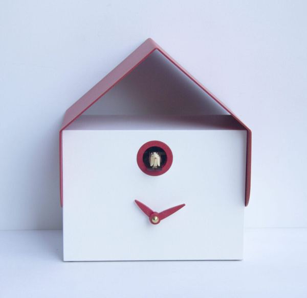 Image shows a small rectangular wall or desk cuckoo clock in white mdf with a red metal room and red hands. The cuckoo peeps our from a small hole under the roof, which is also trimmed in red