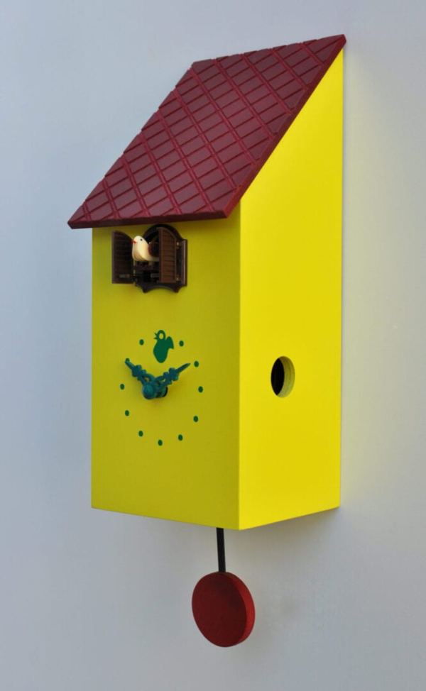 A yellow clock with a red tiled roof which looks like a little bird house. The clock has a red pendulum and a cuckoo pops out of the little house above the clock face