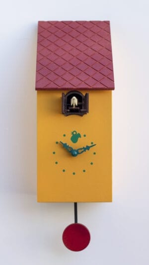 Portofino cuckoo clock in melon yellow with burgundy tile effect roof, red pendulum, grey clock details and cuckoo housed just under the eaves
