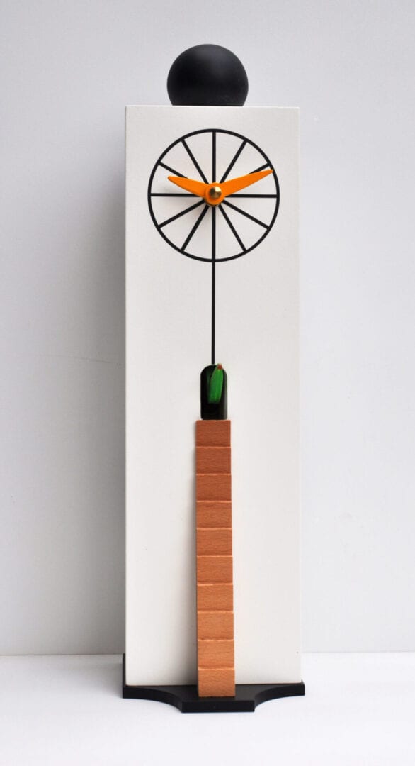 An unusual cuckoo clock designed by Giovanni Pirondini, with a white case, printed with a clockface if the form of a wheel, with a small opening above for the cuckoo, and a latter leading to a small hole below the clock face.