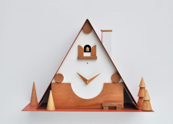 unusual modern cuckoo clock inspired by traditional black forest cuckoo clocks. The clock is in white and wood, with magentic elements that can be repositioned