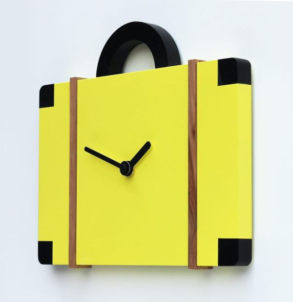 A cuckoo clock which looks like a suitcase, viewed from the right. The clock is sulphur yellow with black detail.