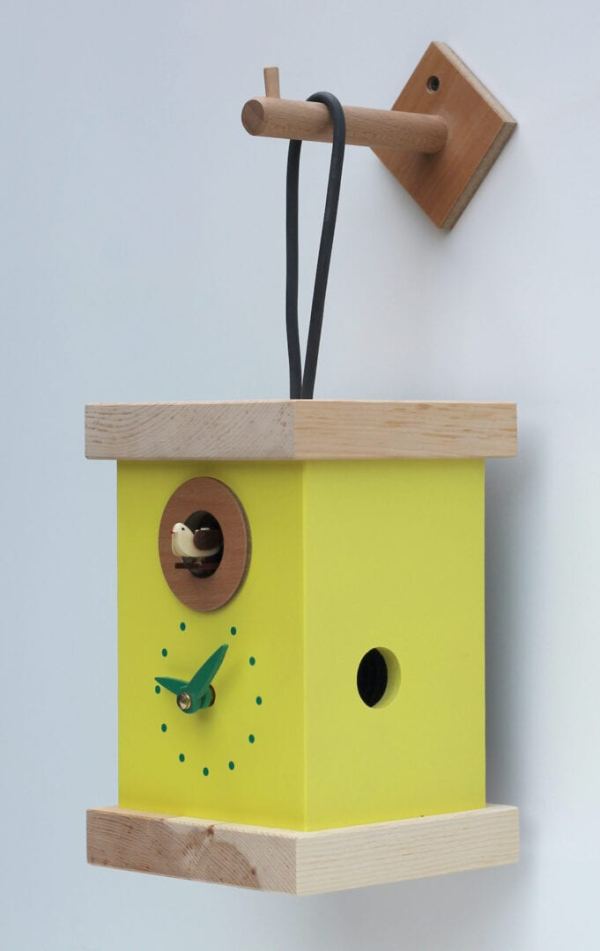 Cuckoo clock in the form of a lantern, hanging from its own hook, The clock is yellow, with green detail on the clock face.