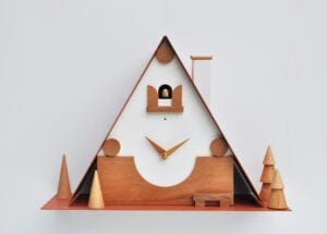 unusual modern cuckoo clock inspired by traditional black forest cuckoo clocks. The clock is in white and wood, with magentic elements that can be repositioned