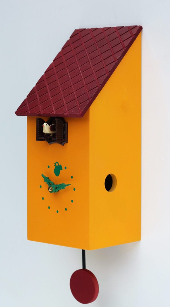 Right hand view of the portofino clock in orange-yellow. The clock has a burgundy roof and pendulum, and green detail on the clockface.
