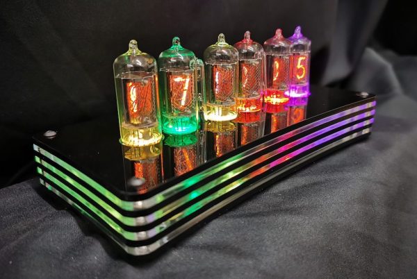 humbug clock with multicoloured lights viewed from the left hand side, showing layered detail of the case and the varied coloured of the nixie tubes when on the Colortime setting