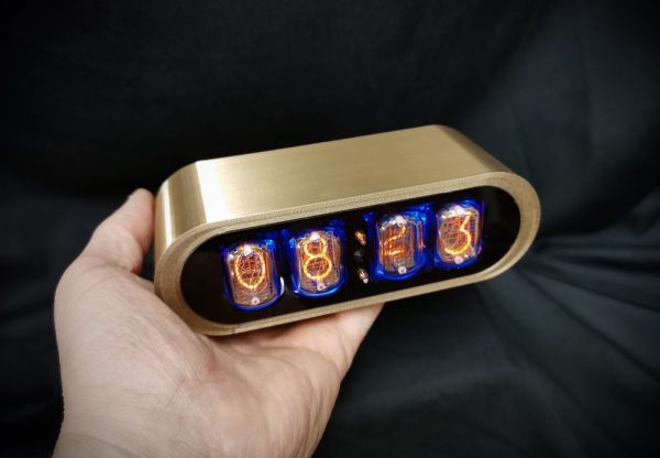 Gold coloured 3D printed case nixe clock, shown in hand for size reference