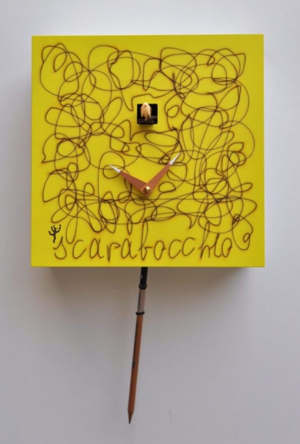 Scribble! A yellow cuckoo clock with a pencil pendulum, which has obviously been used to scribble on the clockface!