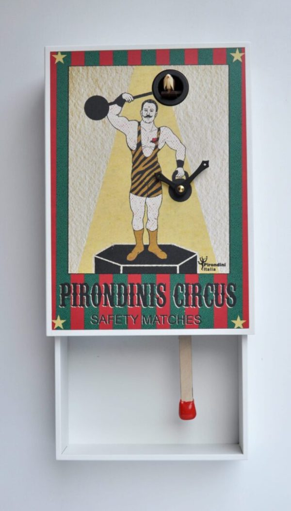 A quirky cuckoo clock in the form of a match box. The label of the box shows a 'strong man' of circus legend,