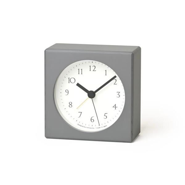 Grey Nuan alarm clock, a small clock made of beech wood and finished in a grey laquer. The clock face is white and the hands and numbers are black.