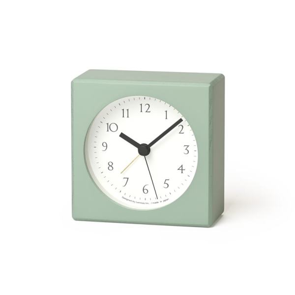A green coloured alarm clock with round face in white with black numbers and hands