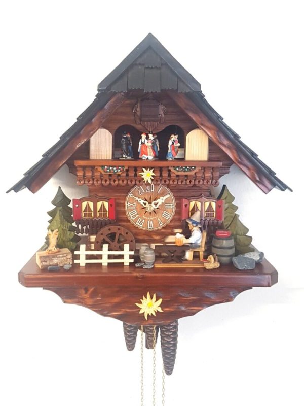 A traditional cuckoo clock with dancers on a balcony, a beer drinker with tankard and an owl sitting on a tree stump